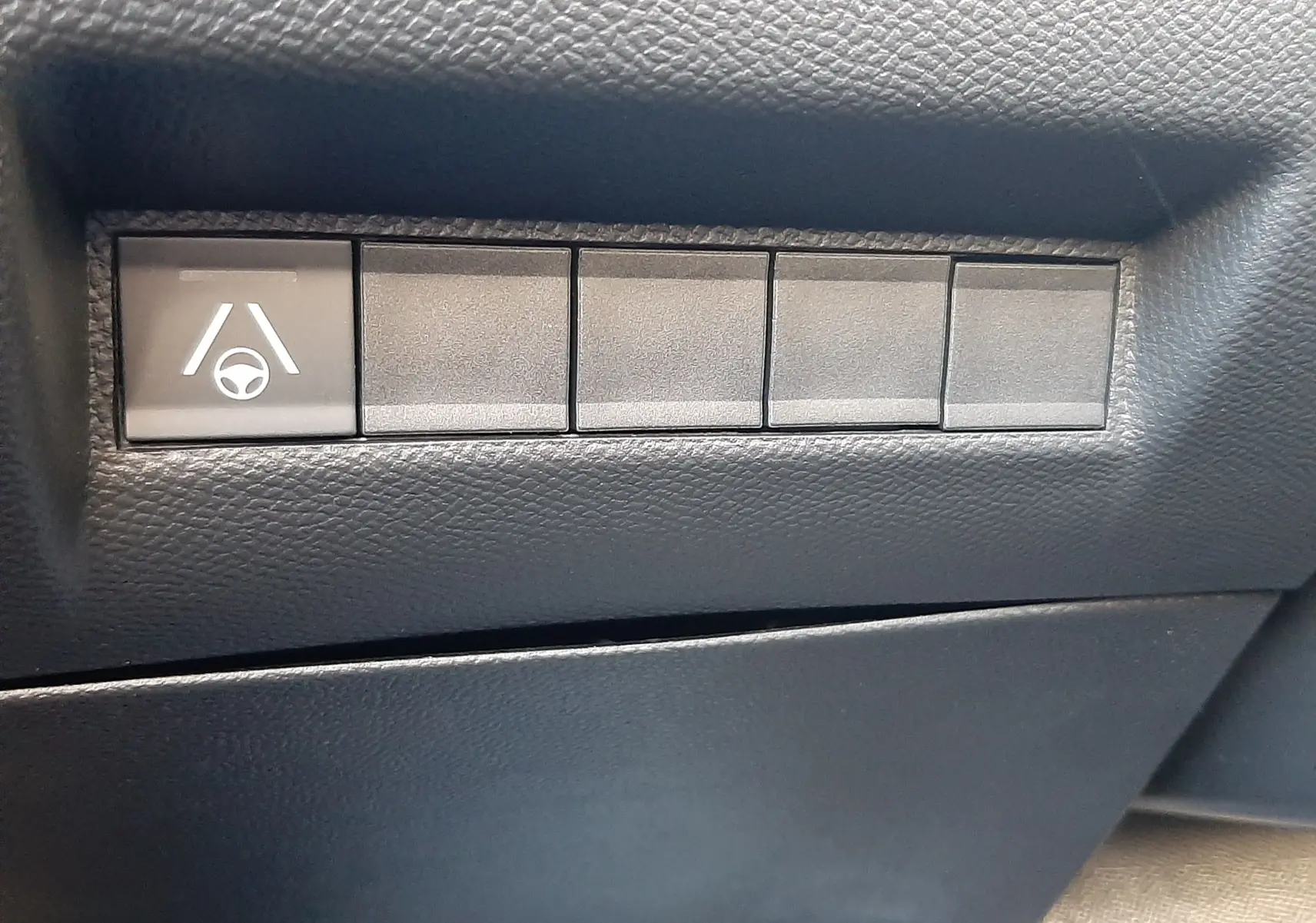 Bouton de commande du système d'assistance au maintien de voie sur tableau de bord noir du Peugeot 2008 hybride 2025.