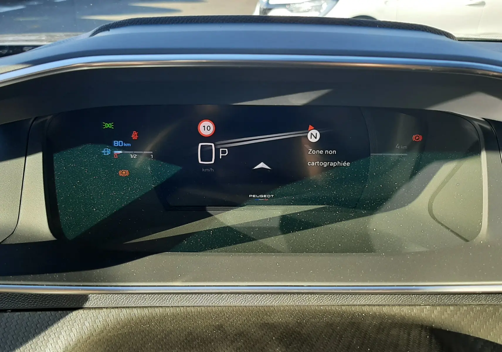 Tableau de bord numérique du Peugeot 2008 gris sélénium, affichant la vitesse à 0 km/h et une zone non cartographiée.