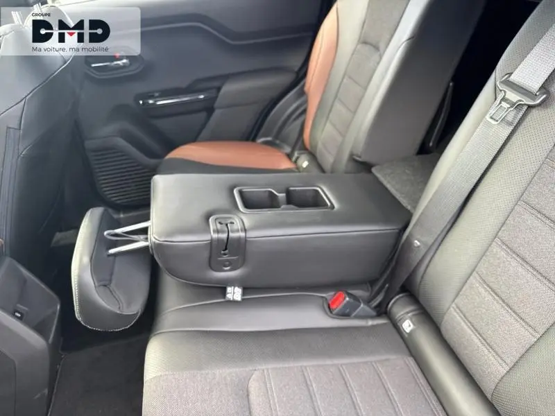 Vue intérieure arrière côté droit du Suzuki Vitara 2026, avec banquette noire et marron, accoudoir central relevé avec porte-gobelets.