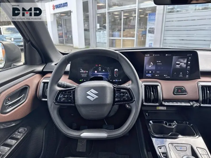 Vue intérieure centrée sur le volant et tableau de bord du Suzuki Vitara 2026, avec habillage marron et écran tactile.