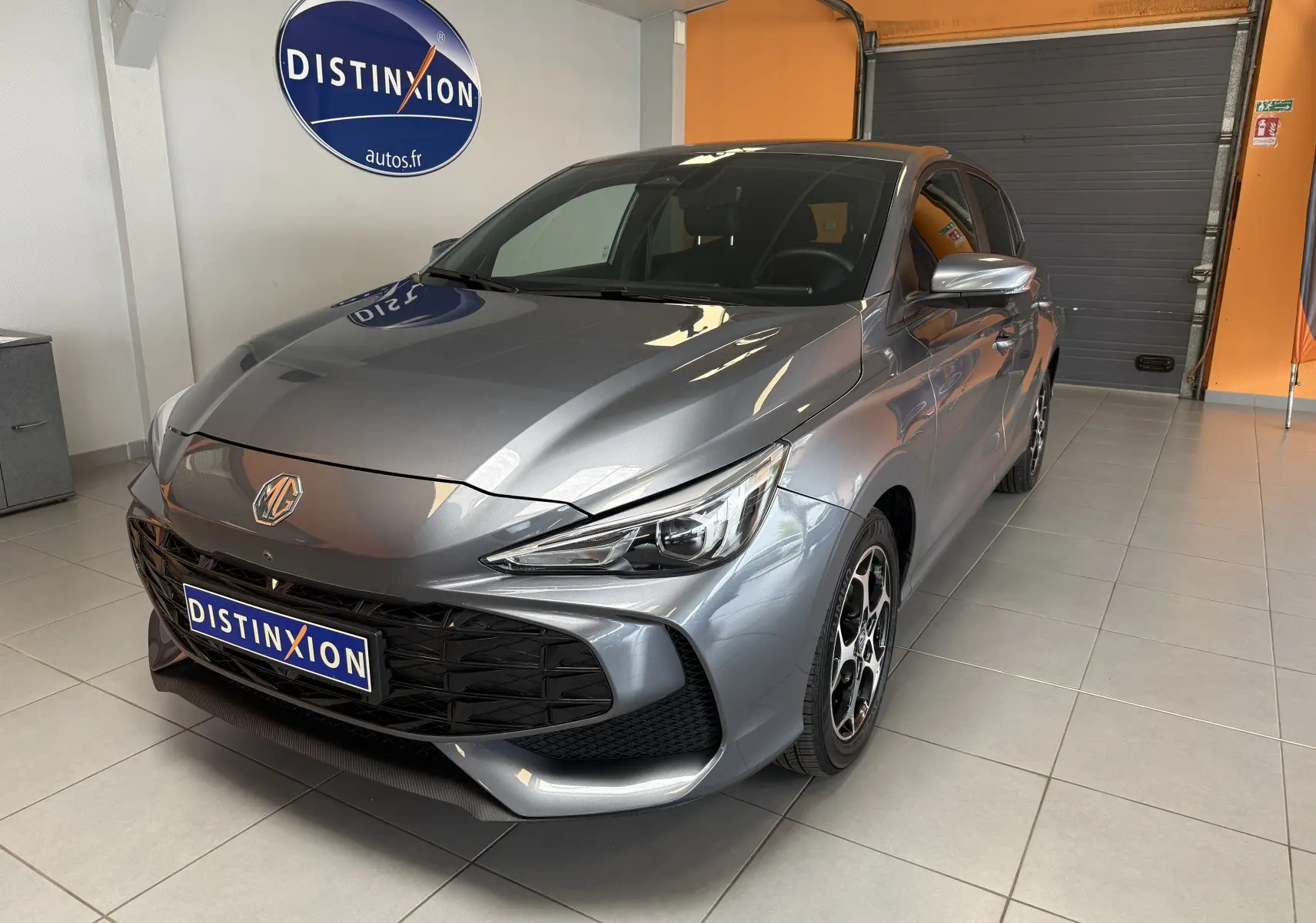 MG3 1.5 L Hybrid+ gris Hampstead en 3/4 avant droit, avec calandre noire et jantes alliage 16 pouces.