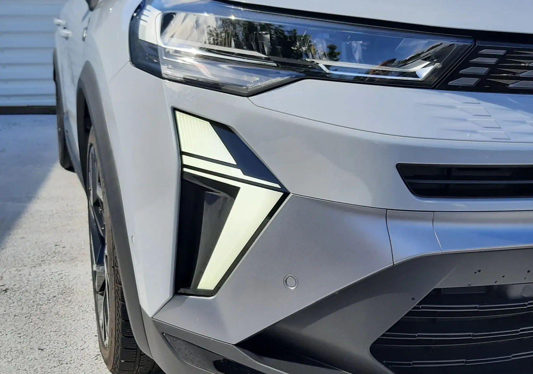 Vue avant gauche rapprochée du Renault Symbioz gris Rafale, mettant en valeur ses phares LED au design angulaire.