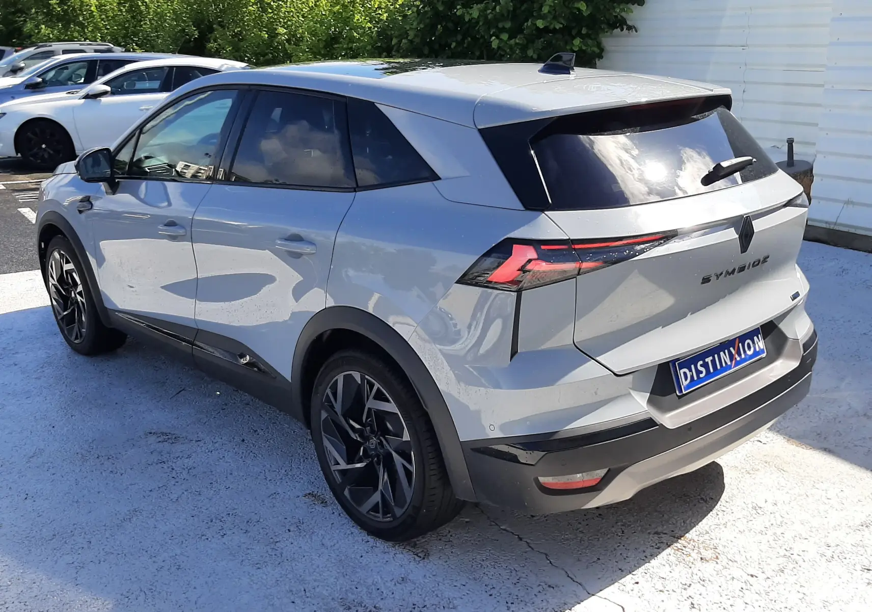 Vue 3/4 arrière droite du Renault Symbioz gris Rafale, soulignant ses feux arrière LED et ses jantes noires.