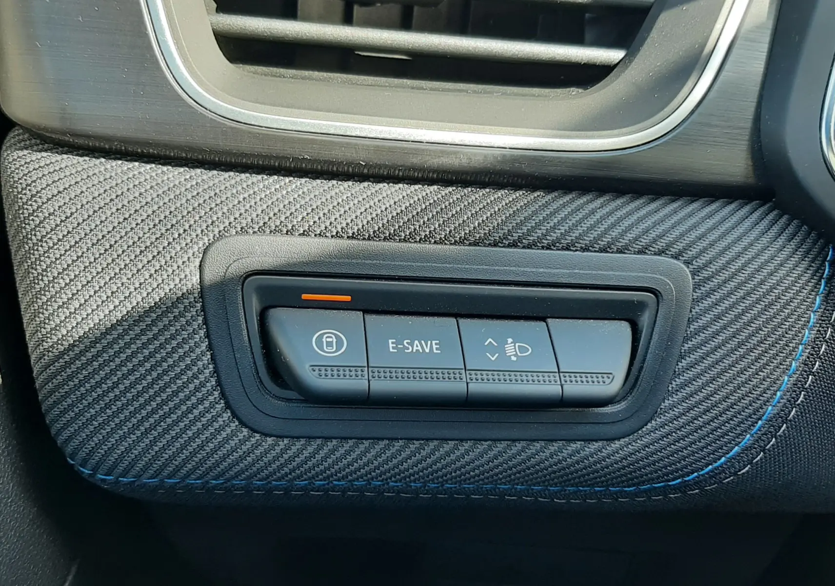 Détail intérieur côté conducteur du tableau de bord gris avec bouton E-SAVE et réglage des phares sur Renault Symbioz hybride 2025.