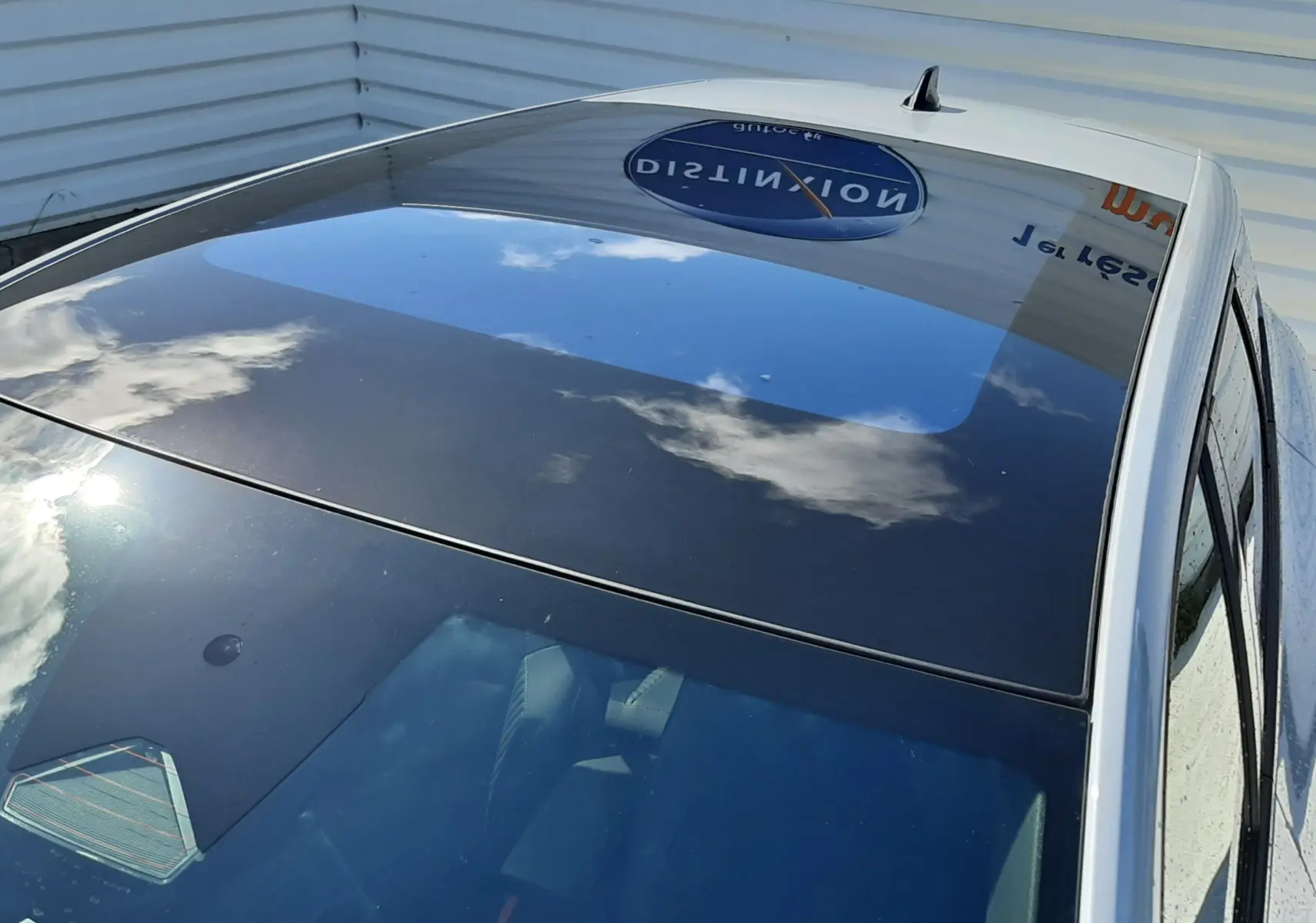 Toit panoramique en verre du Renault Symbioz gris Rafale, vu en plongée depuis l'avant droit, reflet du ciel visible.