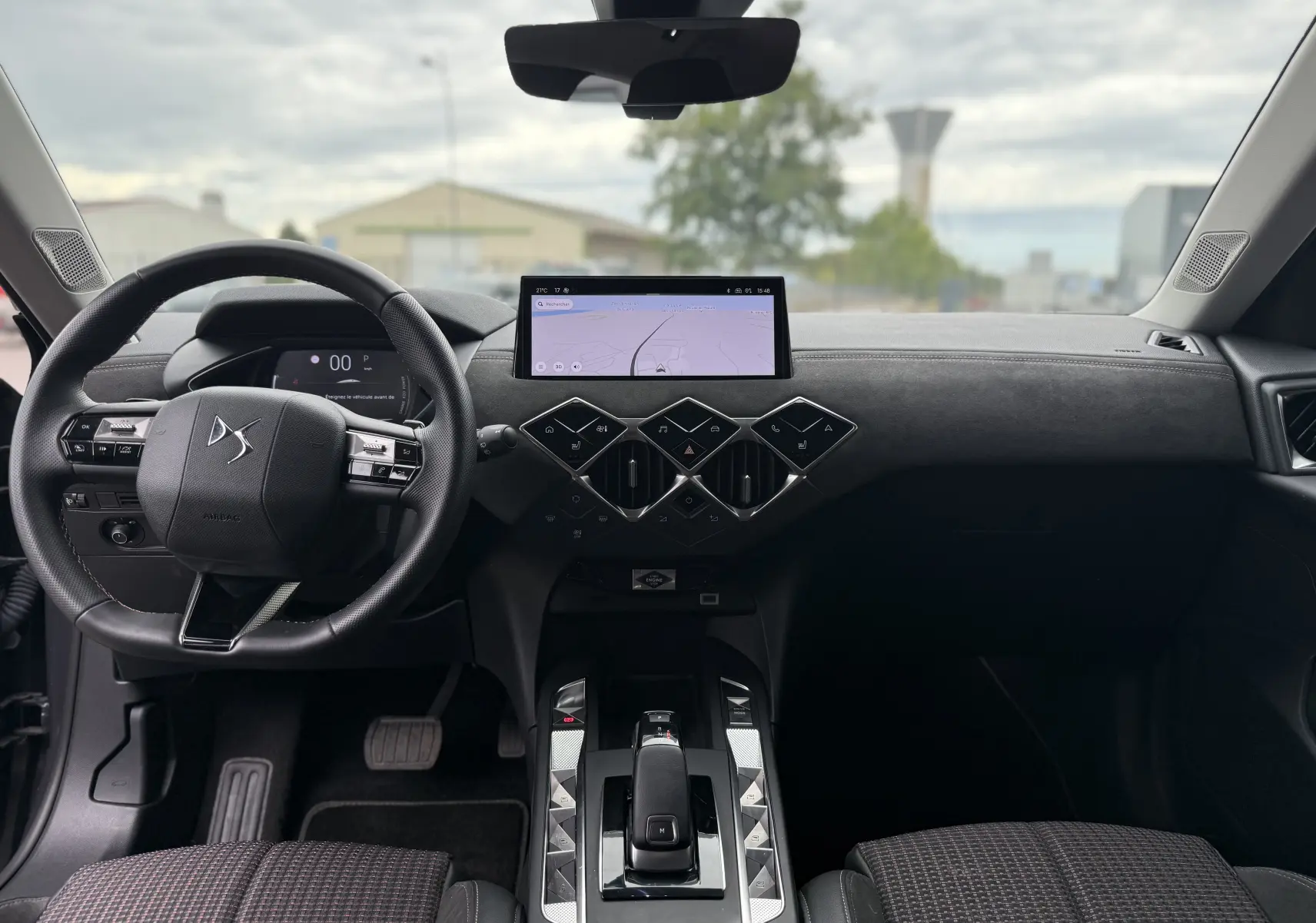 Vue intérieure avant du DS3 hybride 2025, tableau de bord noir avec écran tactile et volant multifonction.
