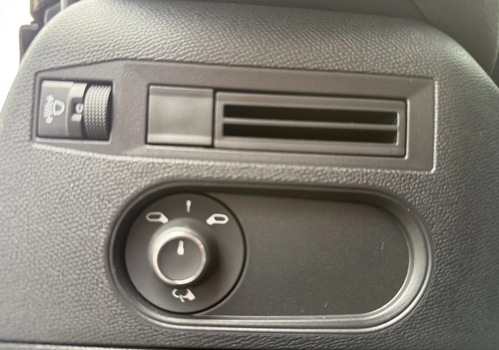 Gros plan sur la commande de réglage des rétroviseurs et la sortie d’air noire à l’intérieur d’une DS3 hybride 2025.