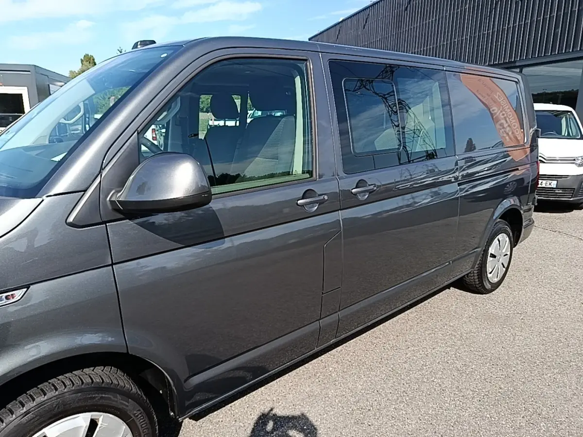 Vue de côté droit d’un Volkswagen Transporter gris foncé 2022, avec vitres latérales teintées et jantes acier.