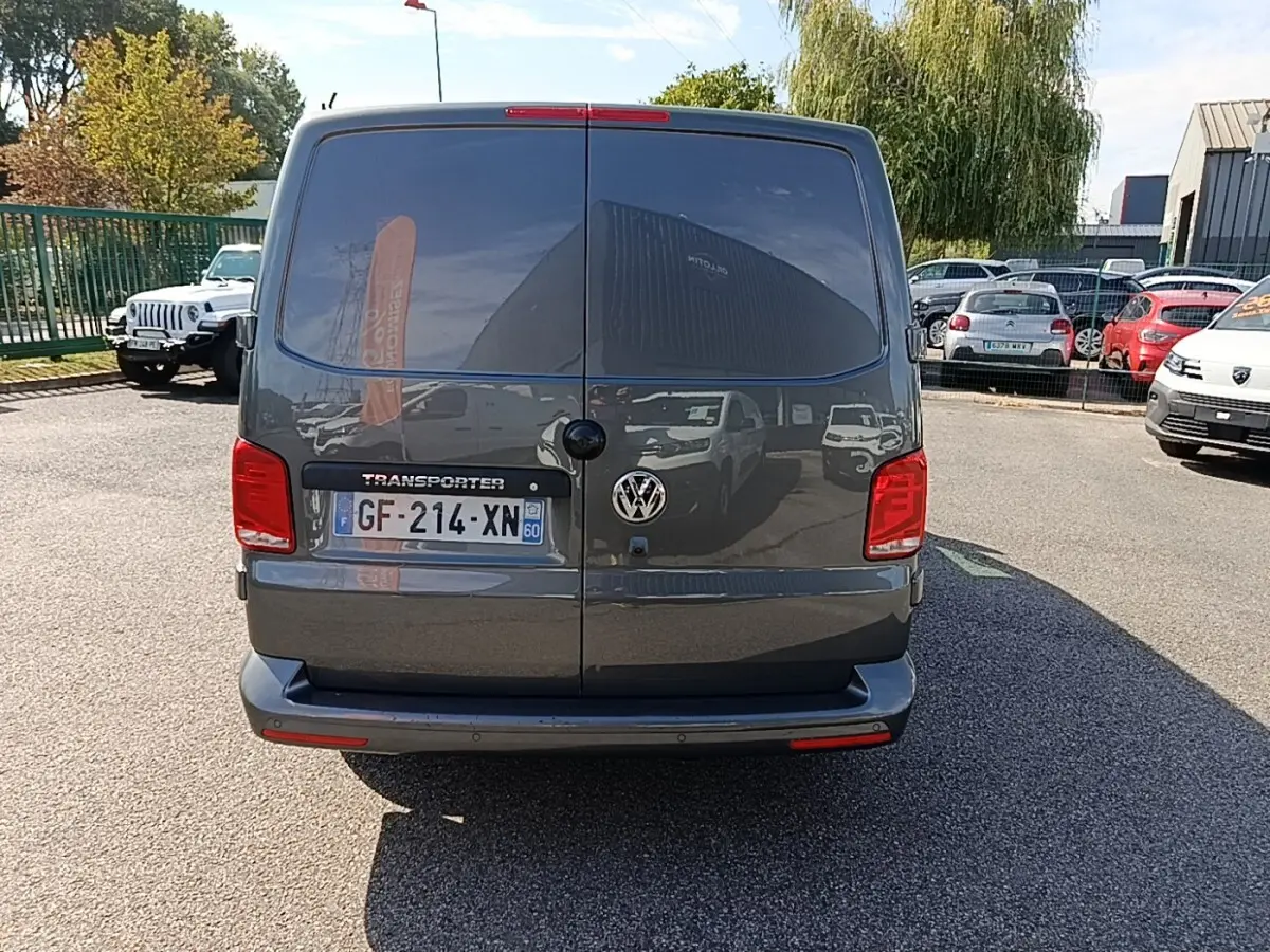 Vue arrière d’un Volkswagen Transporter gris foncé 2022 avec portes battantes et feux rouges visibles.