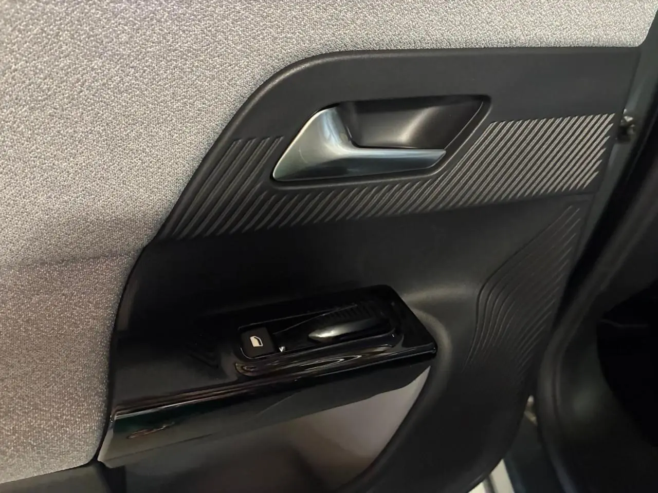 Détail de la porte côté gauche intérieure du Citroën C5 Aircross 2026, avec poignée argentée et commande de vitre noire.