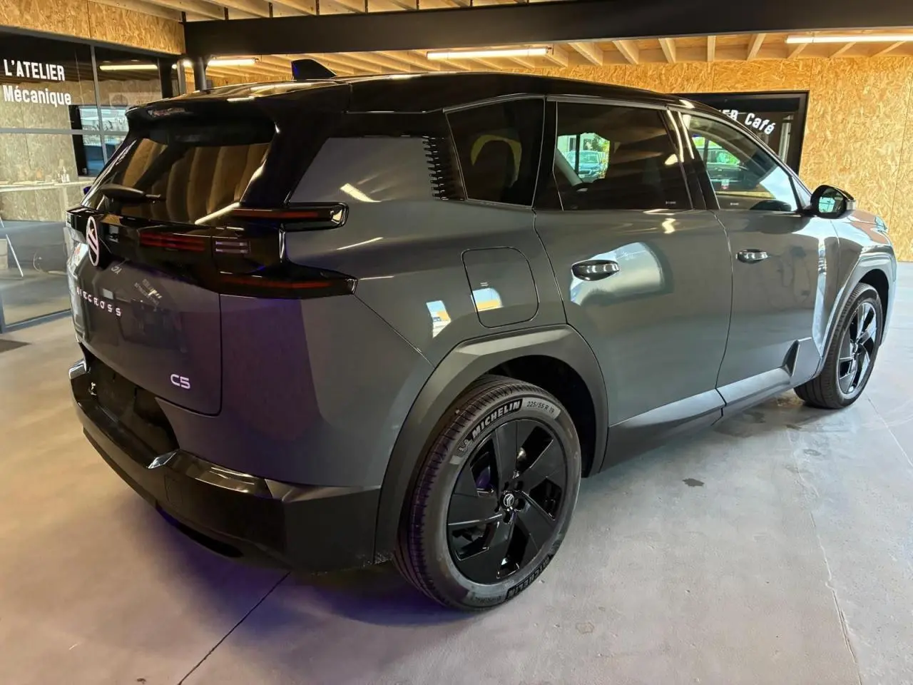 Vue 3/4 arrière droite du Citroën C5 Aircross 2026 vert avec jantes noires et toit noir en intérieur d'atelier.
