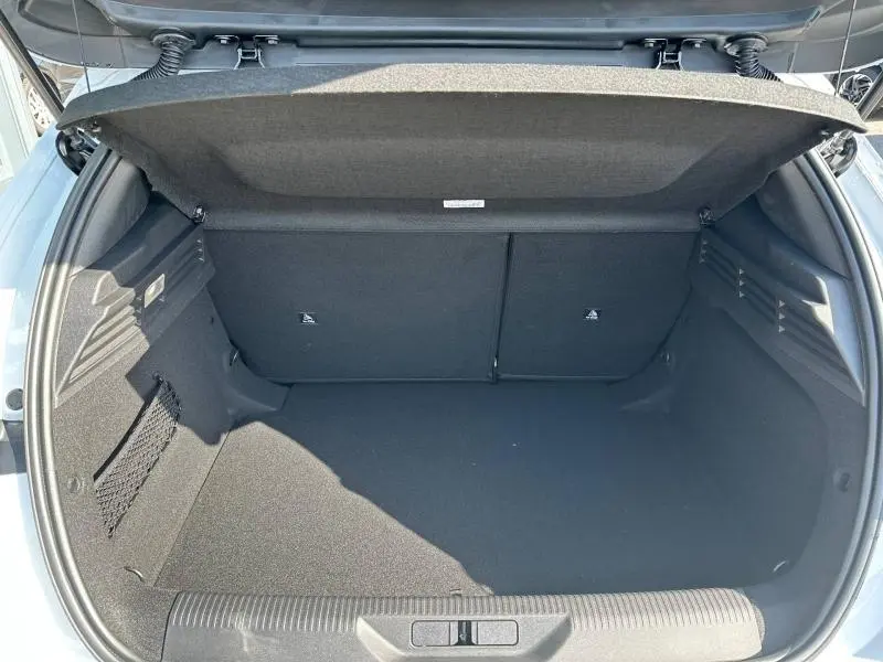 Coffre ouvert vu de l'arrière d'une Peugeot 308 bleu, montrant un espace de chargement propre et bien agencé.