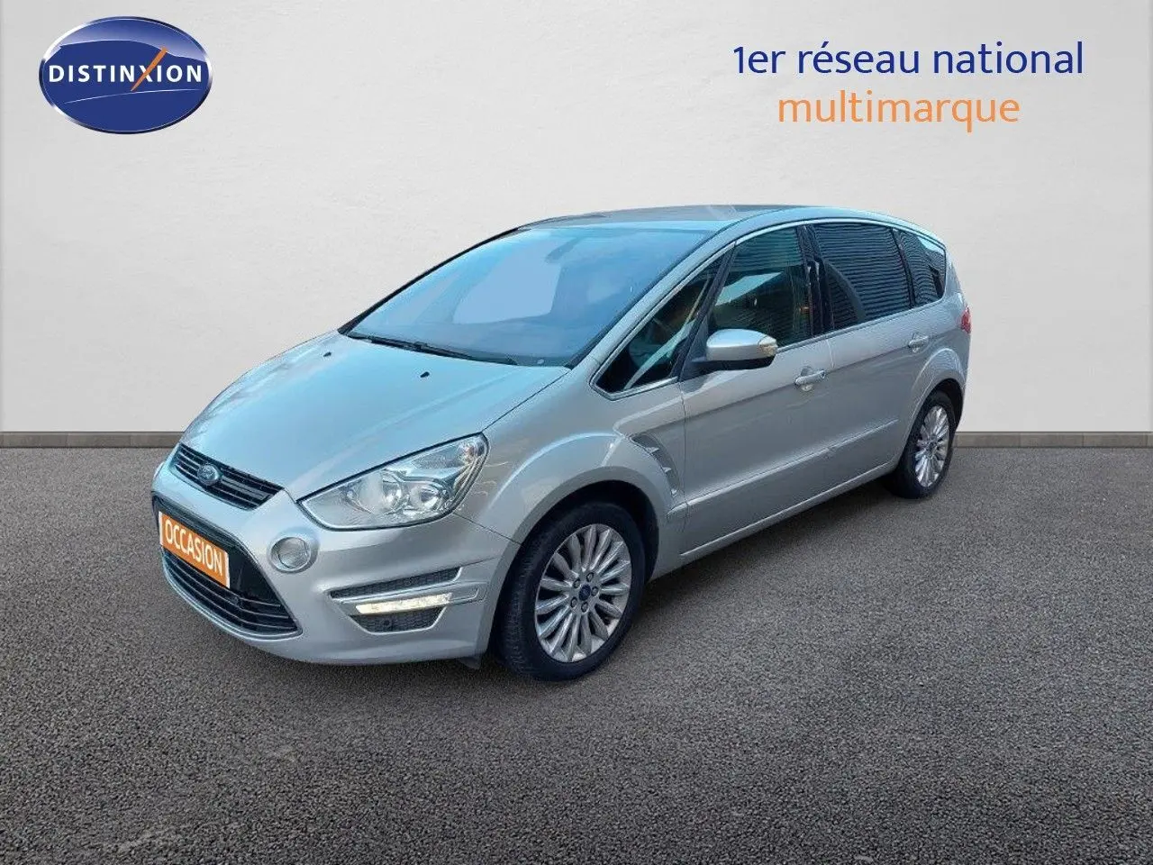 Ford S-Max gris clair métal vu en 3/4 avant droit, avec jantes alliage et feux LED allumés.