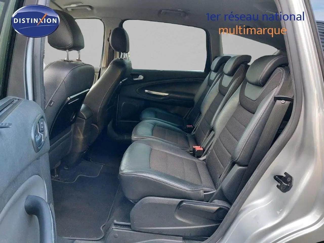 Vue latérale droite de l'intérieur du Ford S-MAX gris clair métal, montrant les sièges en cuir noir et la banquette arrière.