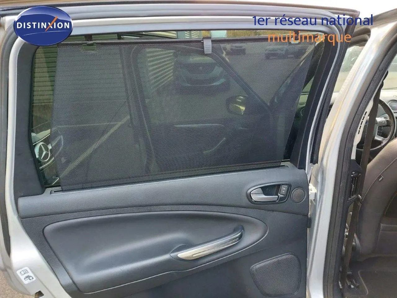 Porte arrière droite ouverte du Ford S-MAX gris clair métal, montrant la garniture intérieure noire avec pare-soleil intégré.