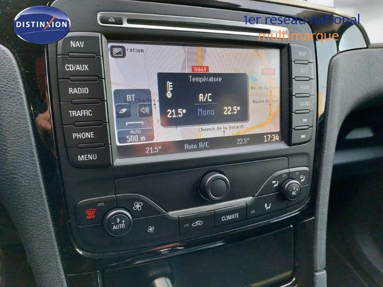 Gros plan sur la console centrale du Ford S-MAX gris clair, affichant la navigation GPS et la climatisation automatique.