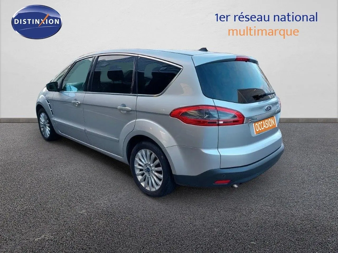 Ford S-MAX gris clair métal vu en 3/4 arrière côté gauche, avec feux arrière allongés et jantes alliage.