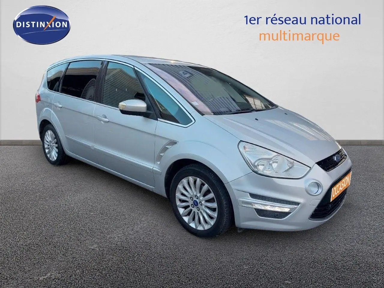 Ford S-Max gris clair métal vu en 3/4 avant droit, mettant en valeur ses phares et jantes alliage.