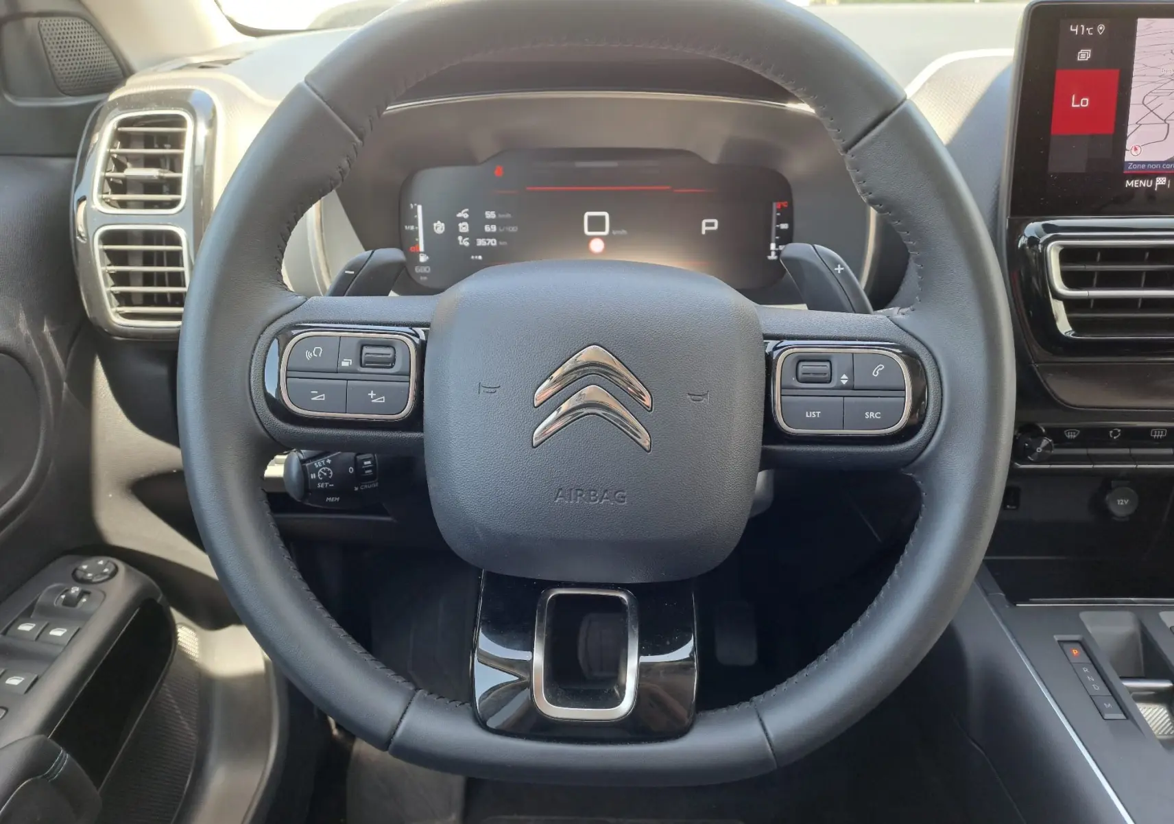 Vue centrée sur le volant noir du Citroën C5 Aircross 2024 hybride, avec tableau de bord numérique et commandes intégrées.