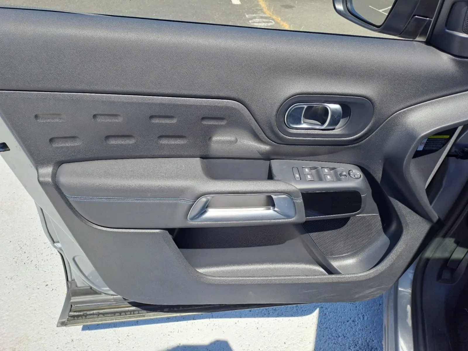 Vue intérieure de la porte avant gauche du Citroën C5 Aircross gris, avec commandes de vitres et poignée argentée.