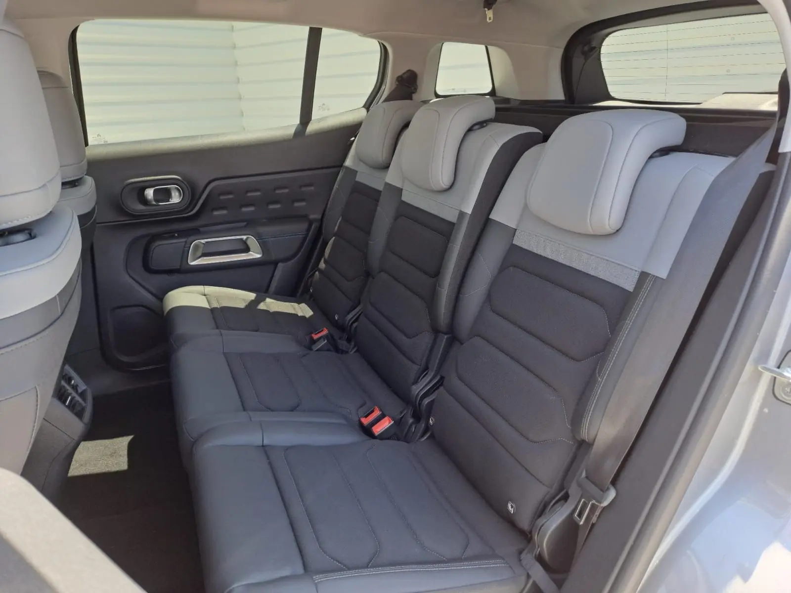 Vue latérale droite de l'intérieur arrière du Citroën C5 Aircross 2024, sièges bi-ton gris clair et noir.