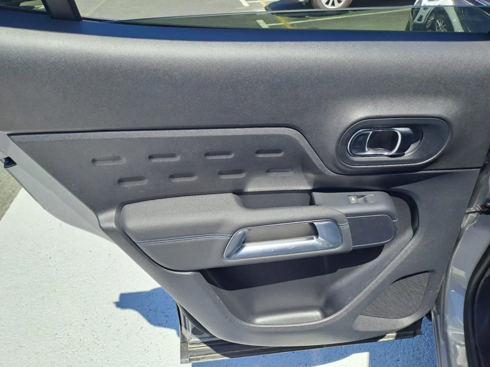 Détail de la porte arrière gauche noire du Citroën C5 Aircross 2024, avec poignée argentée et bouton de fenêtre.