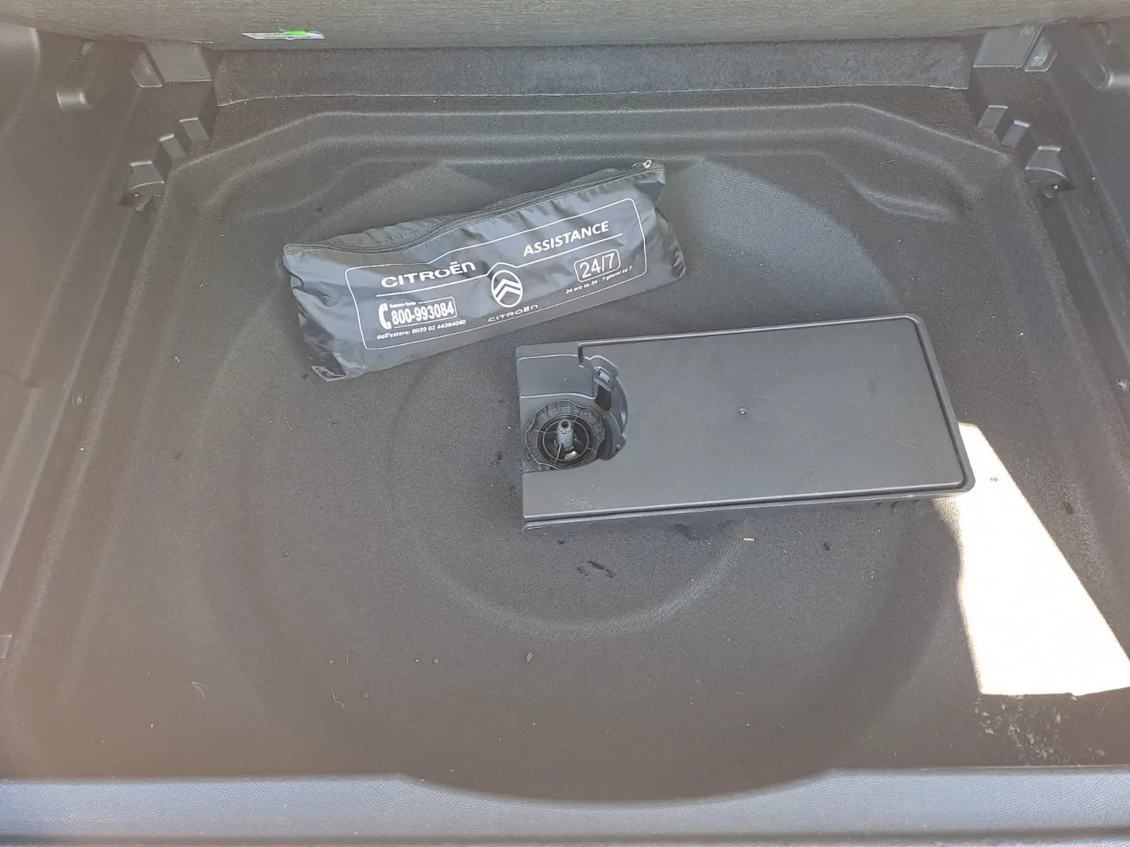 Coffre ouvert d'un Citroën C5 Aircross gris avec sac d'assistance et compartiment de rangement visible au centre.