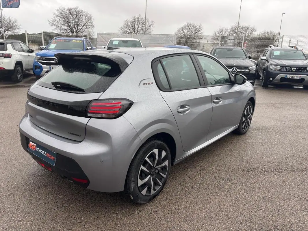 Vue 3/4 arrière droite d’une Peugeot 208 Hybrid gris 2025 avec jantes 16 pouces et logo Style sur aile arrière.