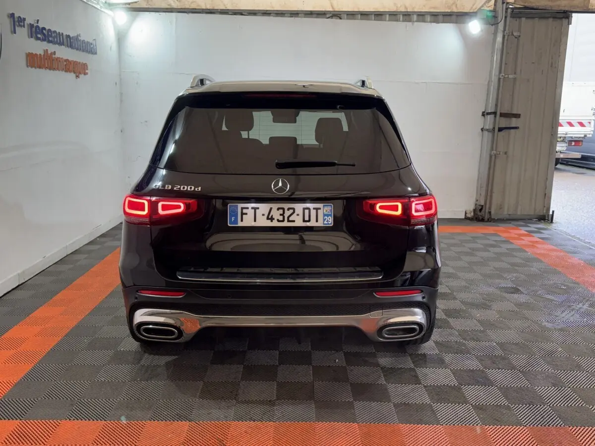 Vue arrière du Mercedes GLB 200 d AMG Line noir avec feux LED allumés dans un garage intérieur.