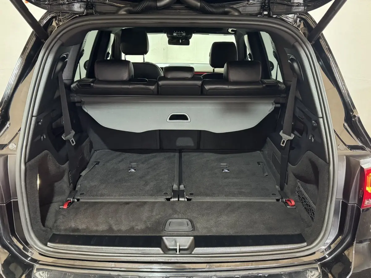 Coffre ouvert d’un Mercedes GLB 200 d AMG Line noir, montrant la 3ème rangée de sièges rabattue et l’intérieur noir.