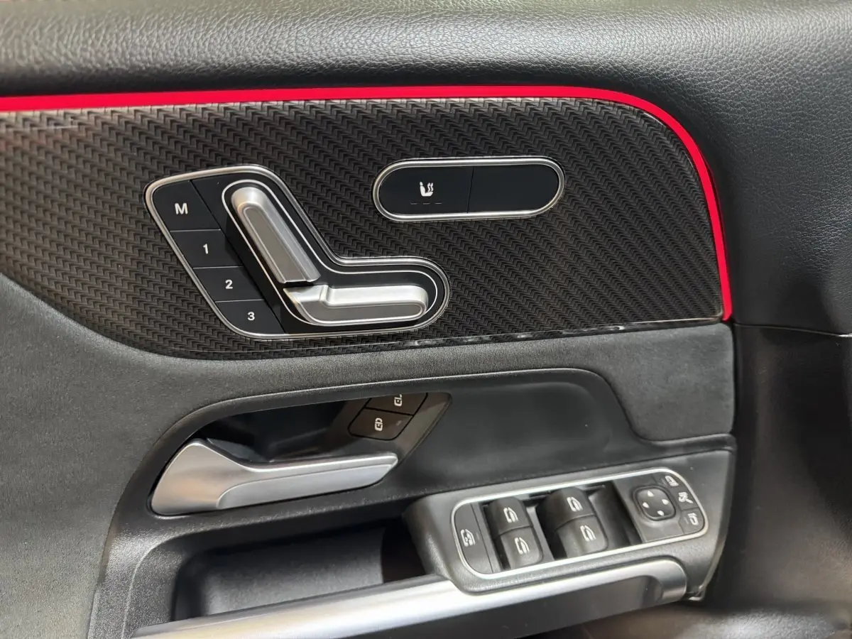 Détail de la porte côté gauche de la Mercedes GLB 200 d AMG Line noire, avec commandes sièges et boutons vitres.