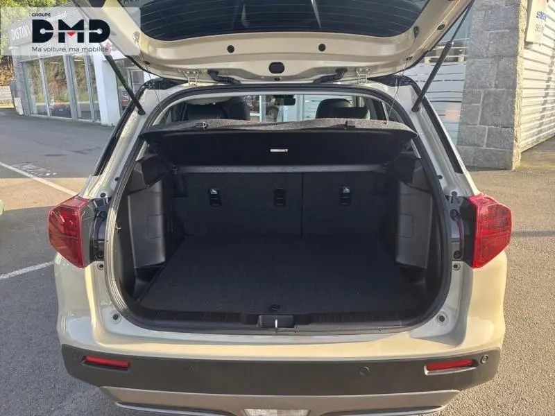 Vue arrière ouverte du coffre du Suzuki Vitara 2026 couleur Savanna Ivory avec intérieur noir et hayon relevé.