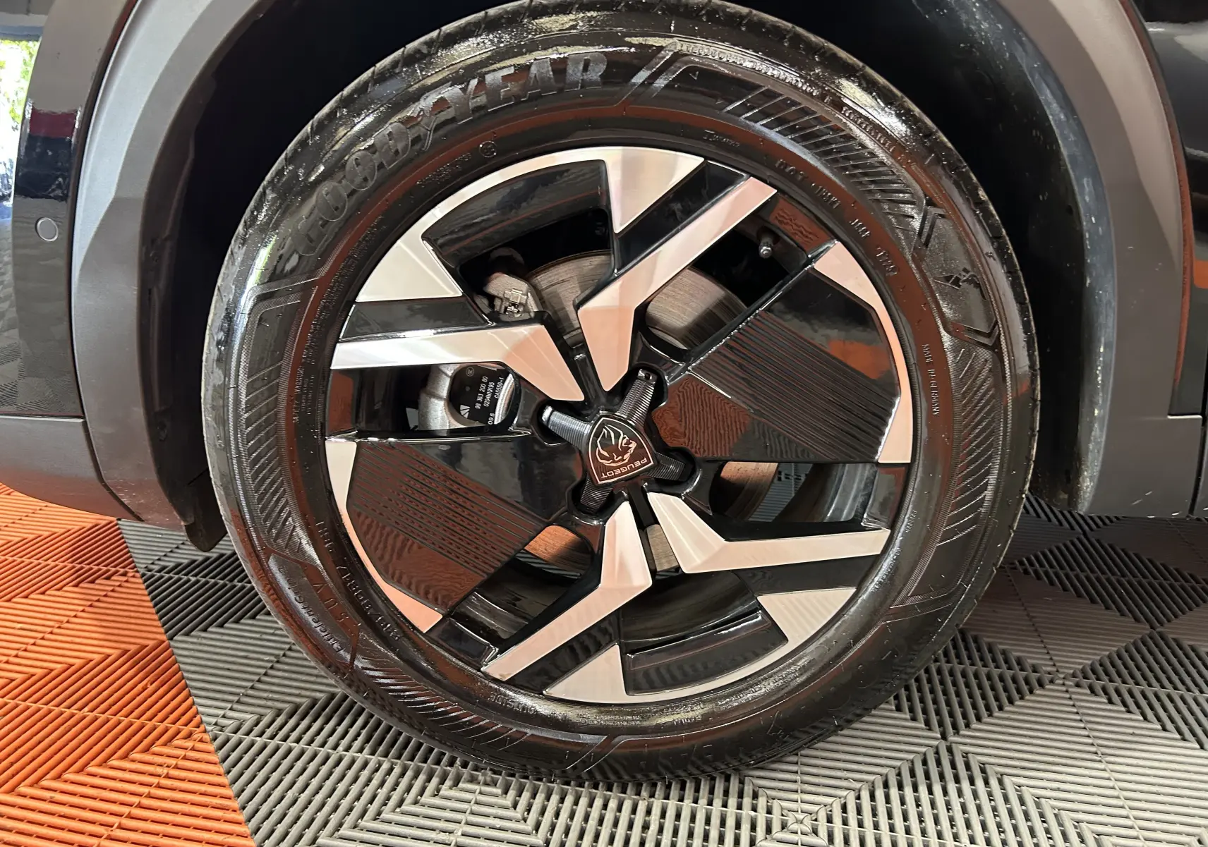 Gros plan sur la roue avant droite noire du Peugeot 2008 Hybrid 136 e-DCS6 GT avec jante alu bicolore stylisée.