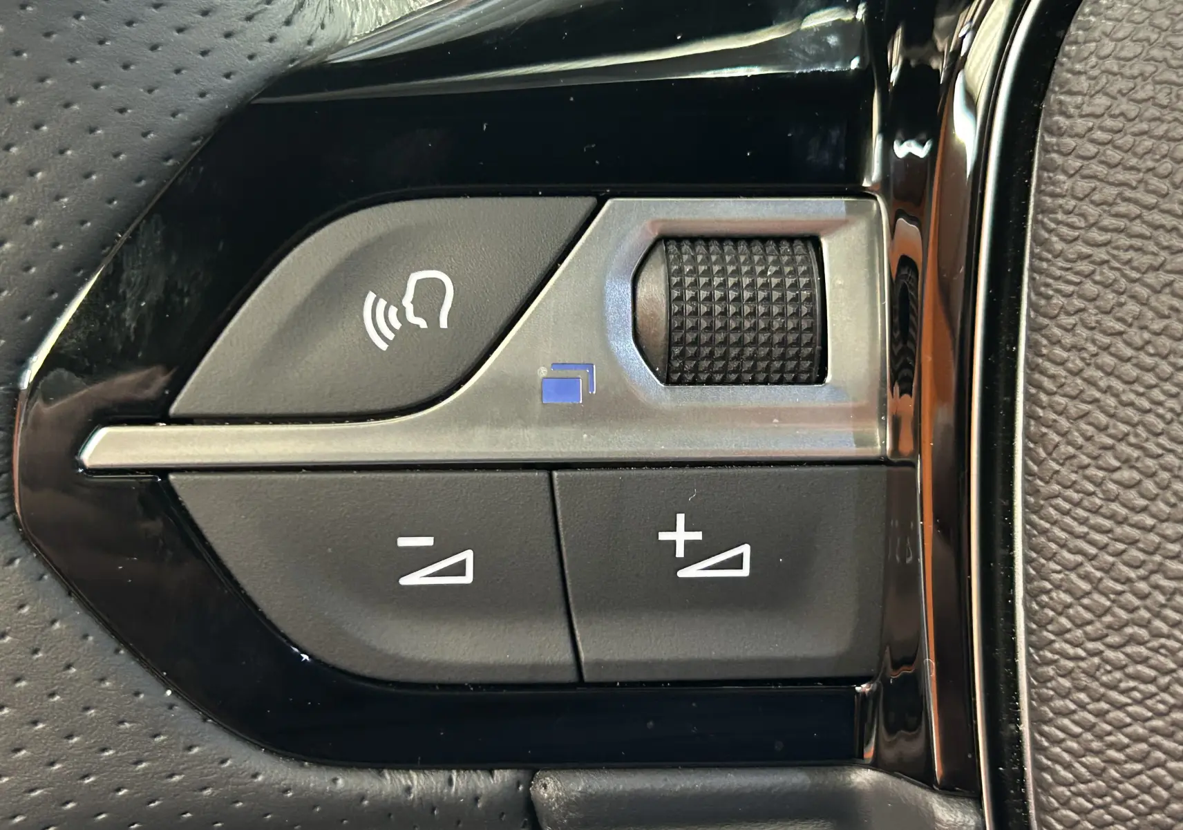 Gros plan sur les commandes du volant noir du Peugeot 2008 Hybrid 136 e-DCS6 GT, avec molette et boutons de réglage.