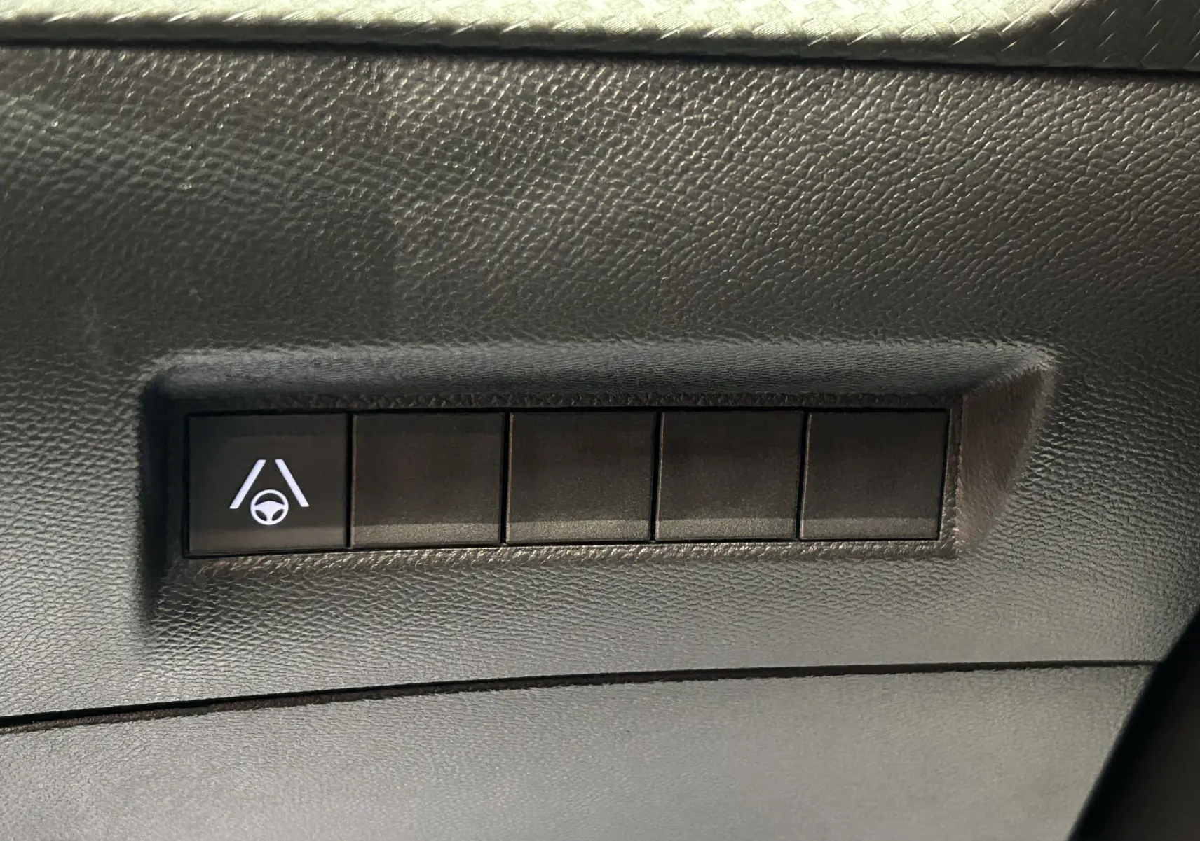 Bouton de commande d'aide au maintien de voie sur tableau de bord noir d'un Peugeot 2008 Hybrid 2025.