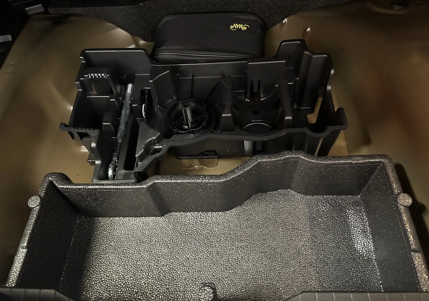 Coffre ouvert en vue plongeante montrant le rangement modulable et les accessoires noirs du Peugeot 2008 Hybrid 136 e-DCS6 GT.