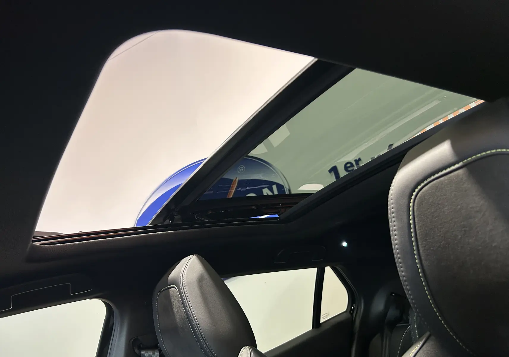 Vue intérieure du toit ouvrant panoramique et des sièges avant en cuir noir du Peugeot 2008 Hybrid 136 e-DCS6 GT noir.