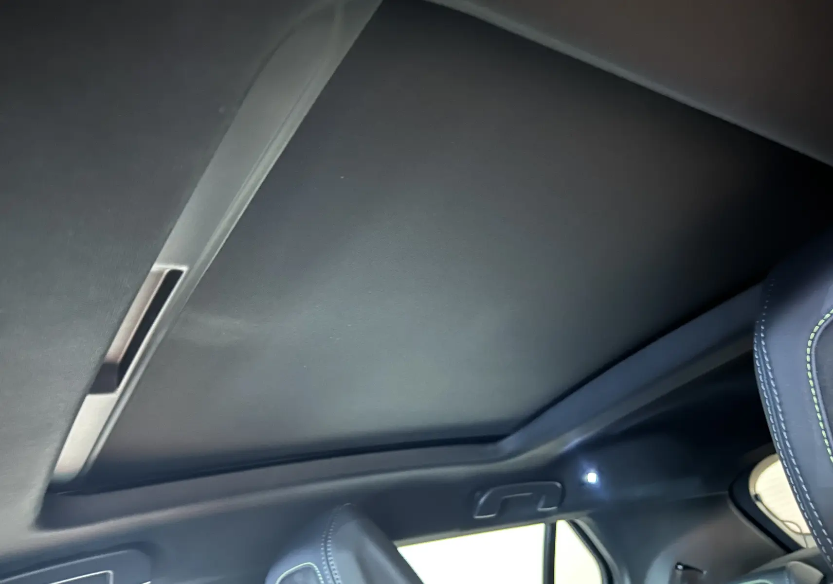 Vue intérieure du toit ouvrant panoramique fermé du Peugeot 2008 Hybrid 136 e-DCS6 GT noir, avec partie du siège avant visible.