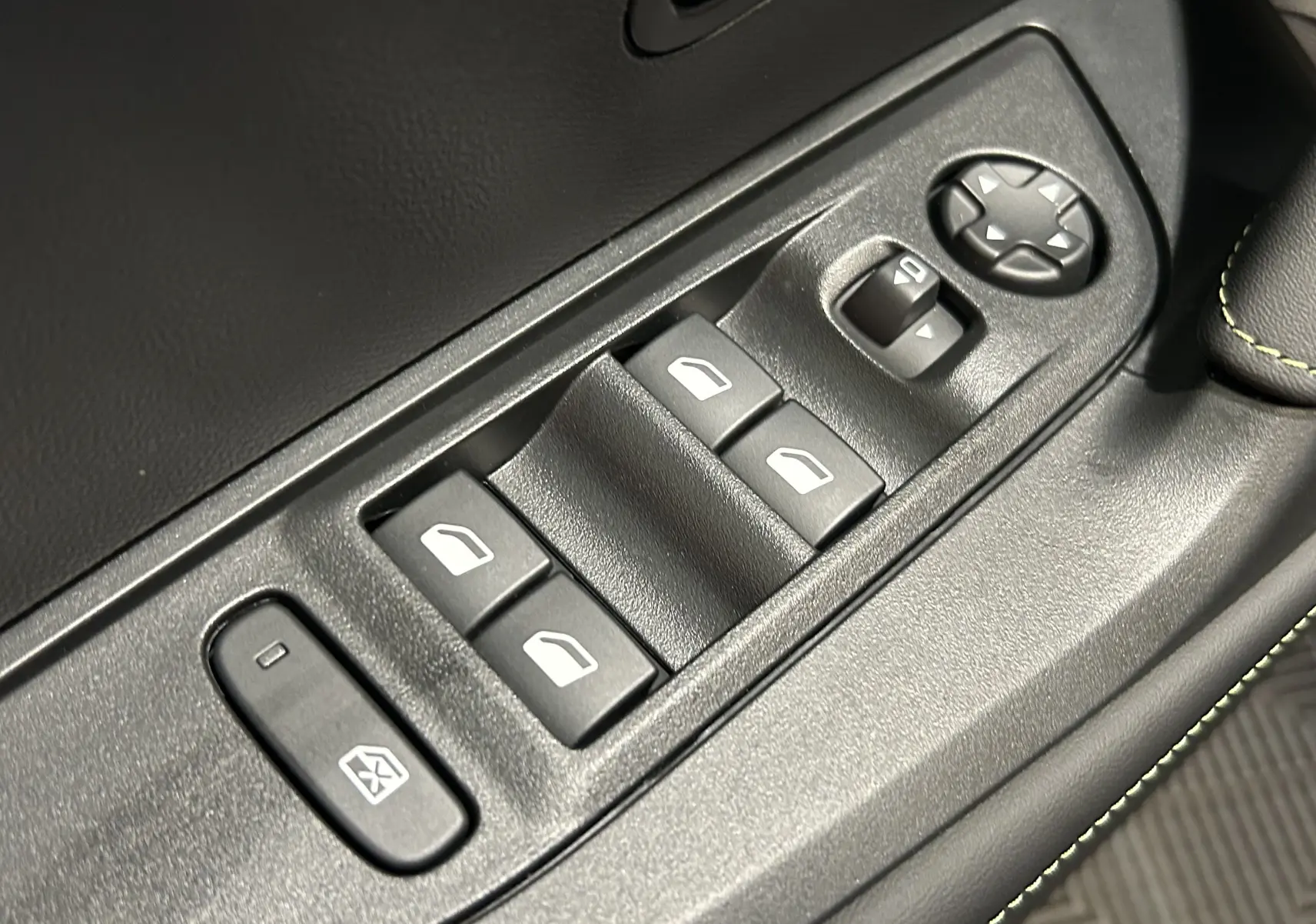 Gros plan sur les commandes de lève-vitres et réglages des rétroviseurs côté conducteur d’un Peugeot 2008 noir.