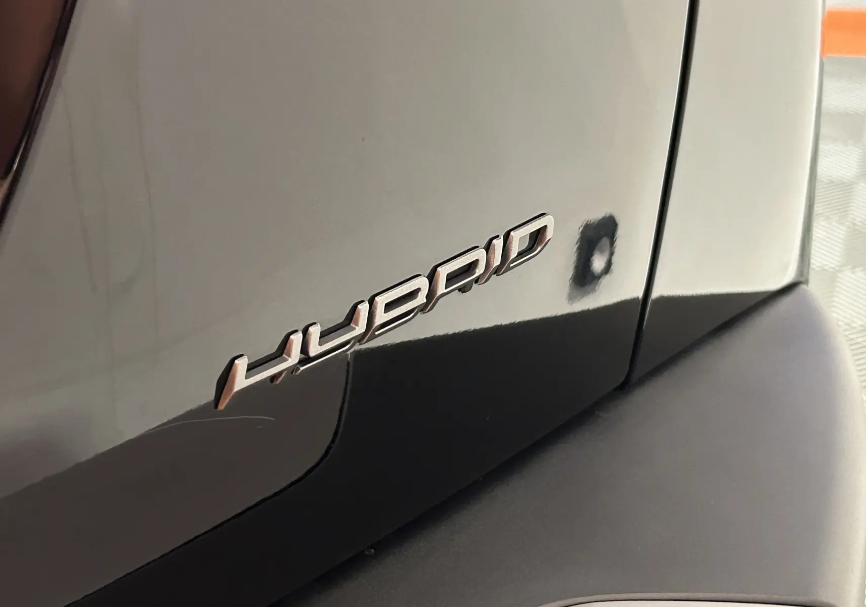 Gros plan sur l’inscription "Hybrid" sur la carrosserie noire côté arrière d’un Peugeot 2008 Hybrid 2025.