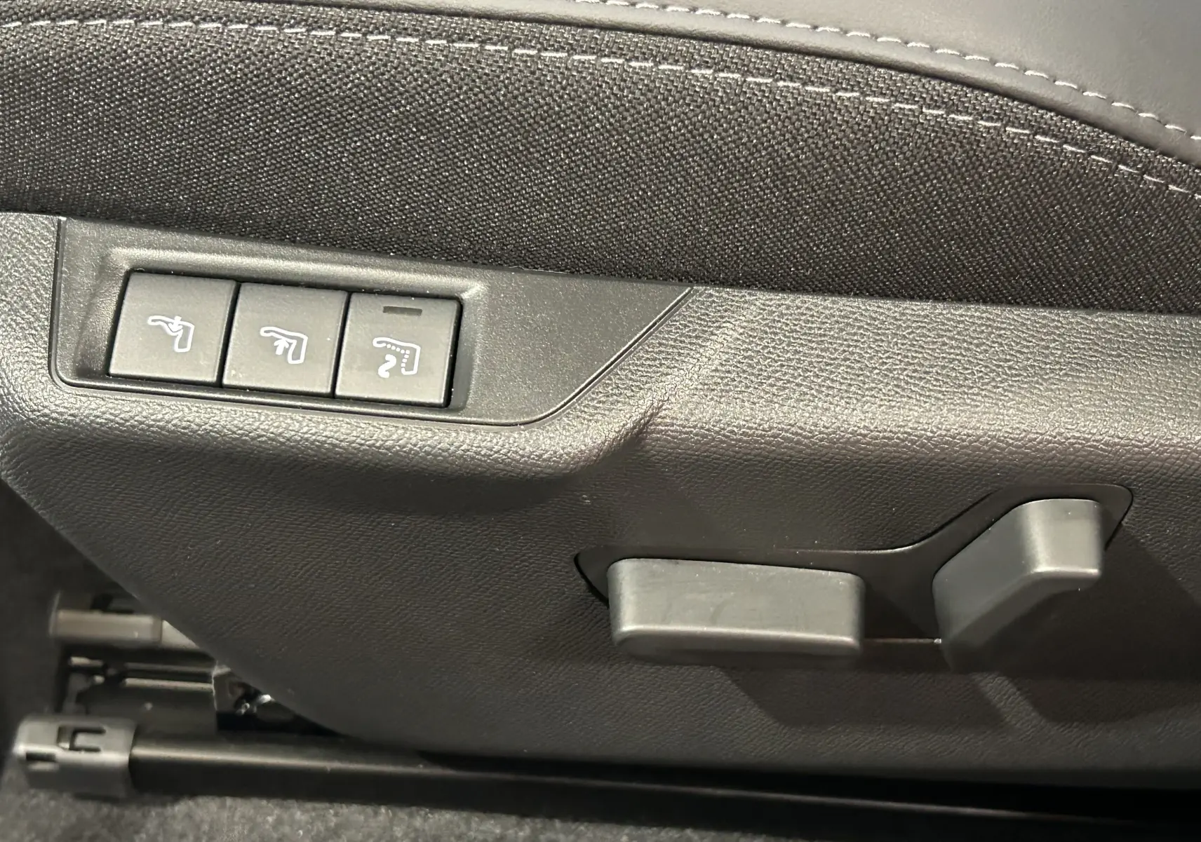 Détail des commandes de réglage électrique des sièges en cuir noir dans un Peugeot 2008 Hybrid 136 e-DCS6 GT.
