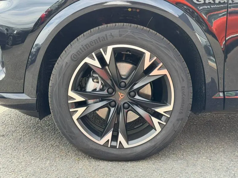 Gros plan sur la roue avant droite d'une CUPRA Formentor bleu, avec jante alu noire et argentée au design dynamique.