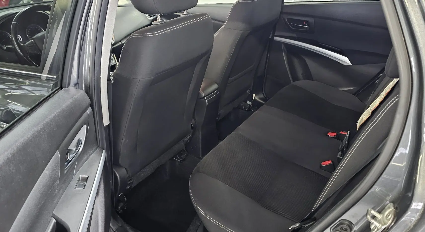 Vue intérieure arrière côté gauche du Suzuki SX4 S-Cross gris 2020, montrant les sièges noirs et les détails de la portière.