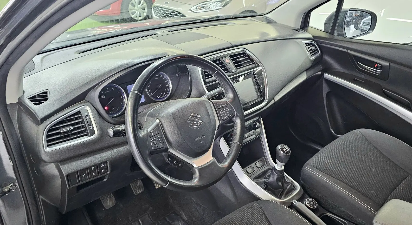 Intérieur du Suzuki SX4 S-Cross gris 2020, vue côté conducteur sur le tableau de bord et levier de vitesse manuel.