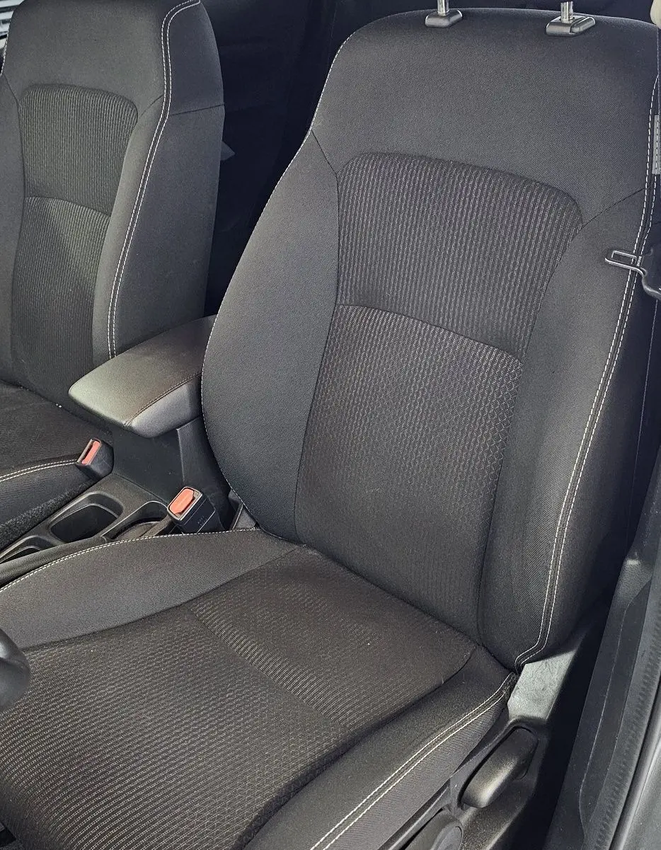 Gros plan sur les sièges avant noirs avec surpiqûres blanches de la SUZUKI SX4 S-CROSS gris 2020, côté conducteur visible.