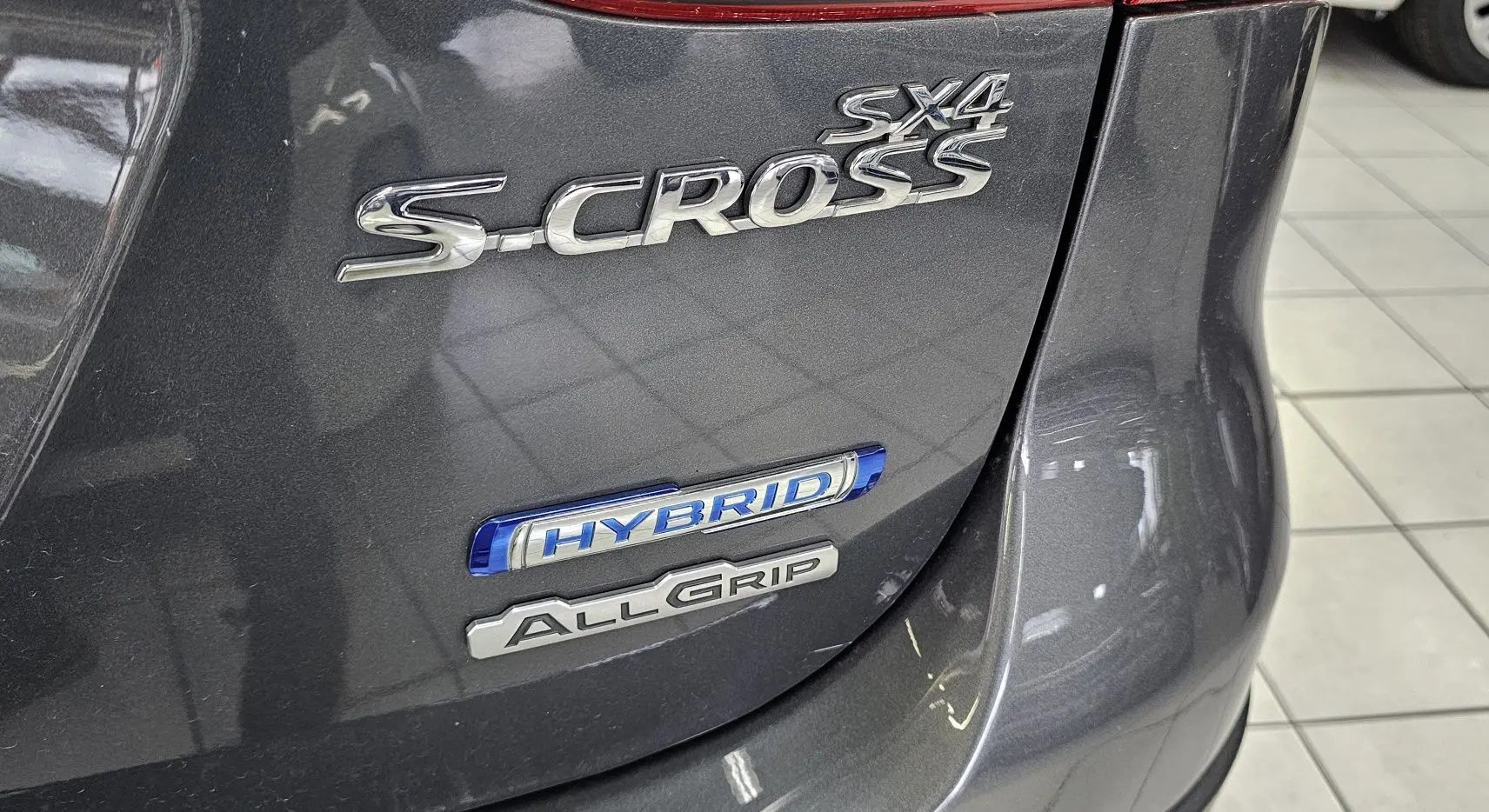 Gros plan sur l'arrière gris du Suzuki SX4 S-Cross avec badges Hybrid et AllGrip visibles.