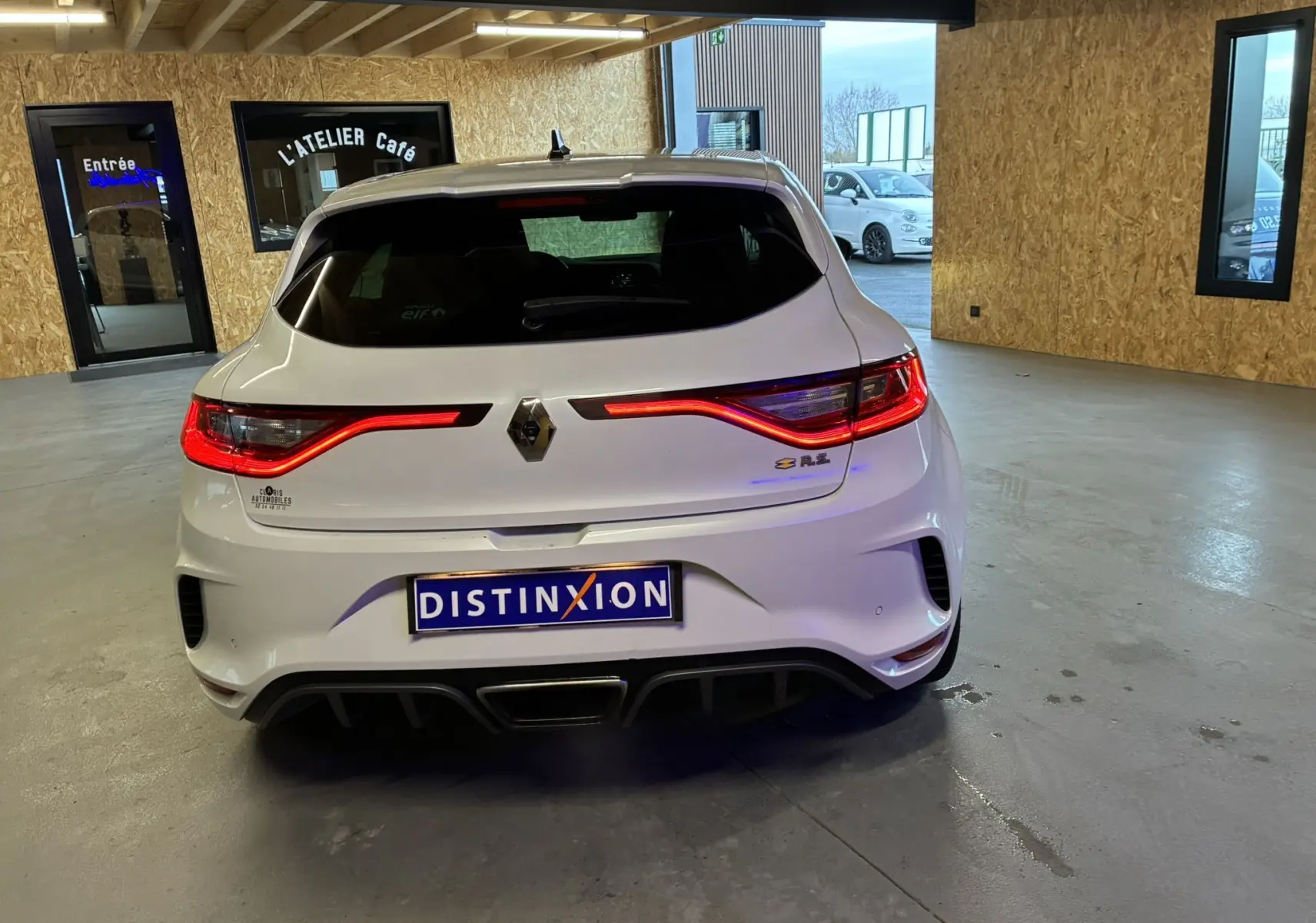 Vue arrière d'une Renault Mégane IV RS 280 EDC6 blanche avec feux LED allumés dans un garage.