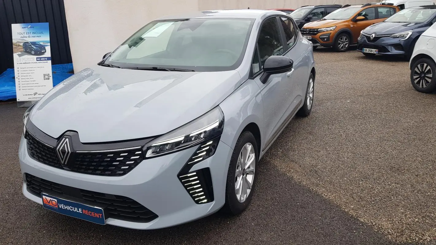 Renault Clio gris vue 3/4 avant droit, avec feux LED distinctifs et calandre noire moderne.