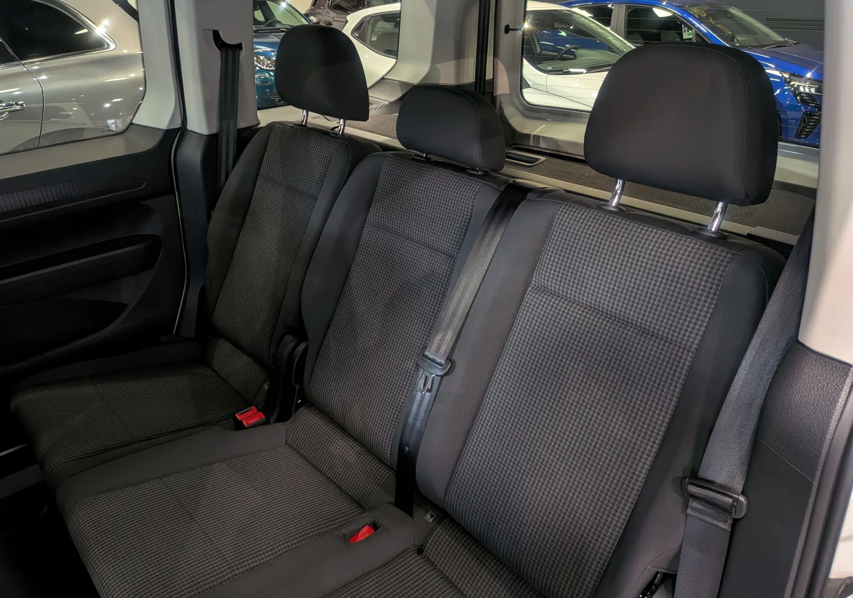 Vue intérieure sur la banquette arrière en tissu noir du Volkswagen Caddy 2025, avec ceintures de sécurité visibles.