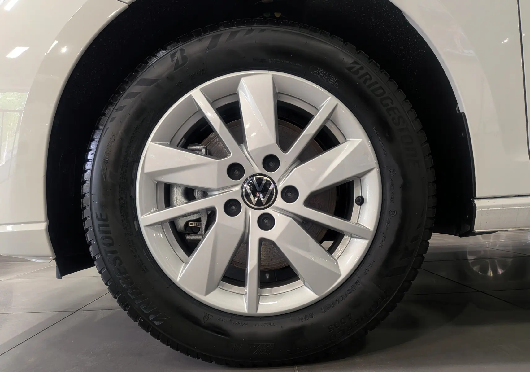 Gros plan sur la roue avant droite blanche d'un Volkswagen Caddy 2.0 TDI 2025 avec jante alliage et pneu Bridgestone.